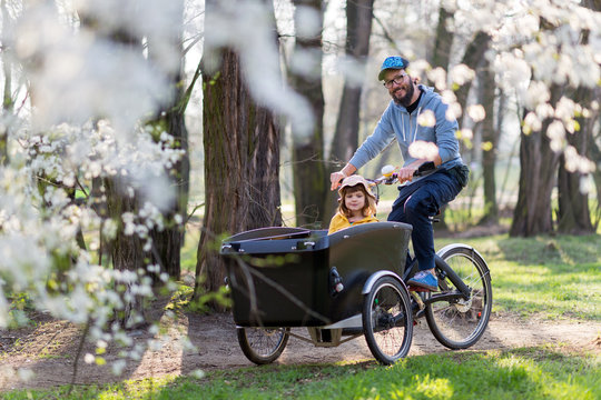 Father and daughter having a ride with cargo bike during spring