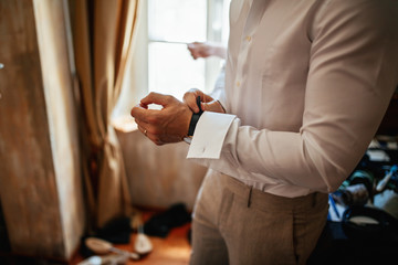 Unrecognizable groom putting his wristwatch and preparing for ceremony.