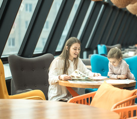 Happy young women mother with children sitting at dinner table and talking in restaurant