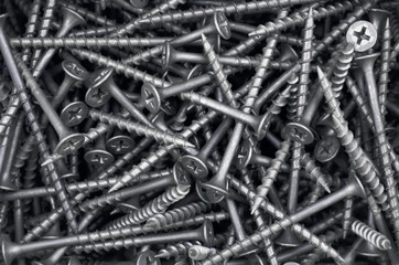 Metal fasteners. Many black tapping screws for construction as an industrial style background, close-up.