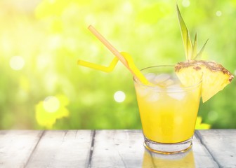 Fresh cocktail with pineapple on wooden table on graden background
