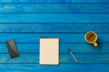 Blue Wooden Desk Table with Notebook, Pencil, Mobile Phone and Coffee Cup, Top View