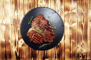 Grilled T-bone steak on stone cutting board.