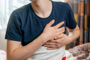 male having heart attack and hold his hand on chest b