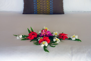 Arrangement of fresh tropical flowers placed on a bed in a luxury hotel in Bora Bora, French Polynesia - obrazy, fototapety, plakaty