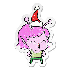distressed sticker cartoon of a alien girl laughing wearing santa hat