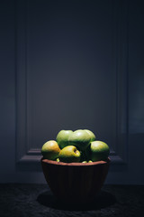 Green apples in a wooden bowl. Dark background. close-up