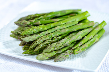 Fresh raw green asparagus vegetable on white board, close up