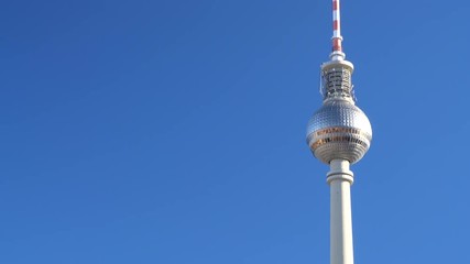 Tilt up on a sunny day from St Marienkirche Church to the Berliner Fernsehturm TV Tower against a blue sky