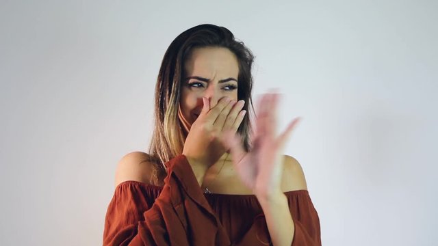 Young woman troubled with the bad smell of the environment. Cover the nose and spread the air.