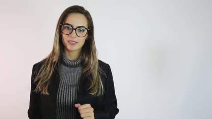 Young woman in glasses looking at camera talking and showing to the side presenting blank copy space for your text or product over white background.