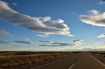 Carretera con cielo azul y nubes blancas al atardecer en la patagonia argentina