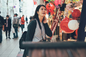 asian girl looking shopping in street vendor in kuromon ichiba in osaka japan. young chinese woman...