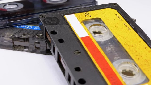 Three Vintage Audio Cassettes Rotate on White Background