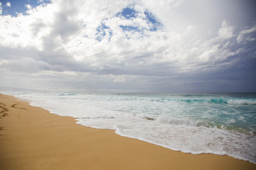 Sandy beach with turquoise ocean and dramatic sky