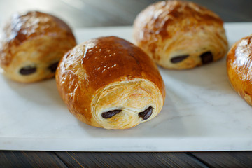 French Chocolate Croissants Fresh From the Oven Served on a White Marble Cutting board on a Rustic Wood Table