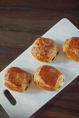 French Chocolate Croissants Fresh From the Oven Served on a White Marble Cutting board on a Rustic Wood Table