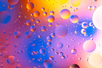 purple and orange oily drops  in water with colorful background, close-up 