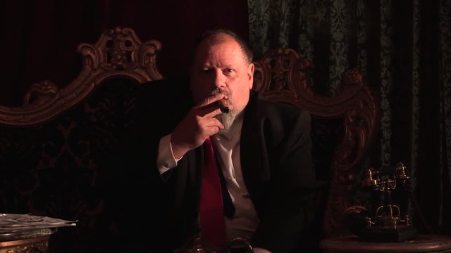 Businessman leans forward for a better look while smoking a cigar