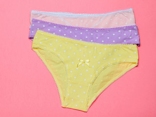 Three women's cotton panties on a light pink background. Fashionable concept. Beautiful lingerie.