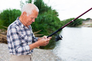 Mature man angling at riverside