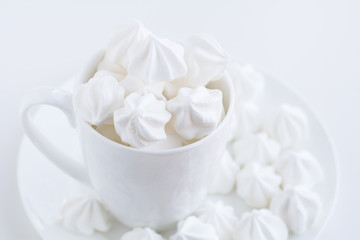 The white merengue in the white tea cup on white background, top view