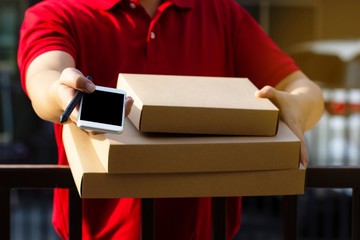 The postman stood holding a parcel box and handed it to us at the front door and handed the phone to sign the receipt.Delivery service concept.