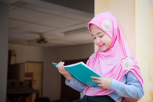 Pretty Muslim Girl Reading Book And Smiles.