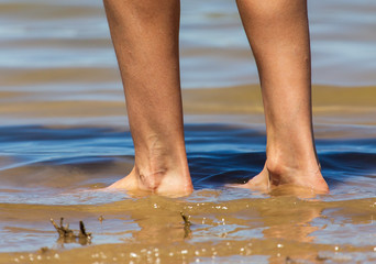 Feet of a girl walking by the sea