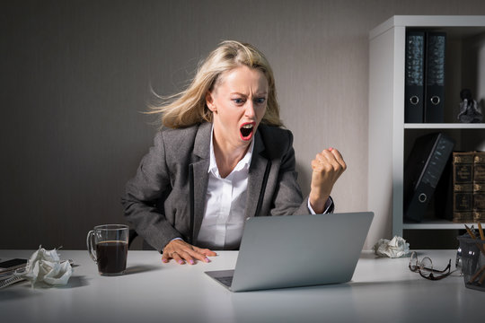 Woman angry at her laptop computer at work