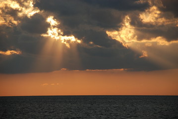  the sun through the clouds over the sea