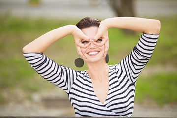 Young happy woman sitting on a bench outdoors and looking in to a camera