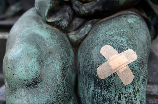 Pflaster an einer Kupferstatue am verletzten Fu&szlig; mit Wunde