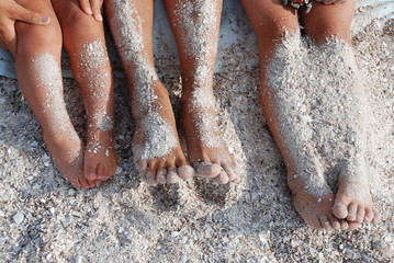 children's tanned legs in the sand on the beach