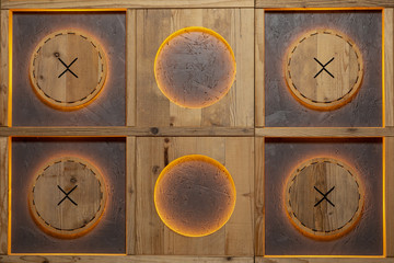 Decorative wall handmade with orange lighting made of wood in the form of squares and circles in them.
