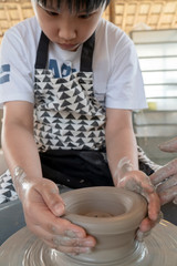 Asian kid work clay with the ceramic wheel.