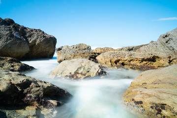 Waves smoothed by long exposure washing in around rocky foreshore at base of Mount Maunganui, Tauranga