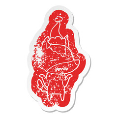 cartoon distressed sticker of a wolf showing teeth wearing santa hat