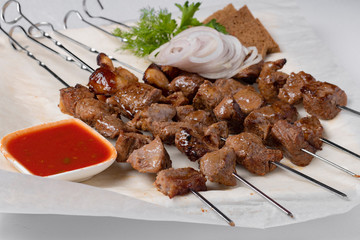 barbeque on sticks with onion rings and sauce, close up