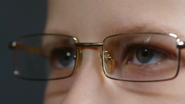 Extreme close up face of young primary school boy wearing glasses and looking at something at distance