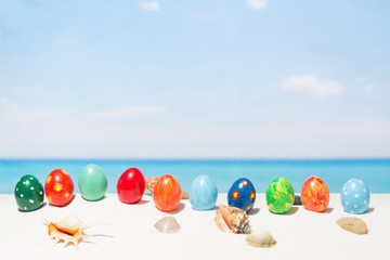 Easter on tropical beach background. Eggs on the white sand. Vacation and travel concept in spring