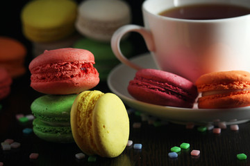 Bright macaroons with a cup of coffee against dark background