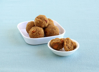 Laddu or maladdu, an Indian sweet dish for festivals like Maha Shivratri, Dasara and Diwali, in a tray and broken pieces of a laddu in a bowl.