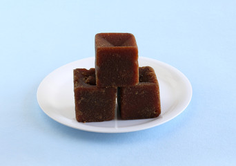 Jaggery, which is of organic type and an healthy Indian sweetener, on a white ceramic plate.