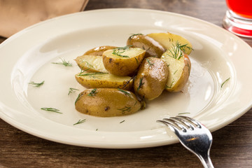 Baked potato wedges on white plate on wooden table