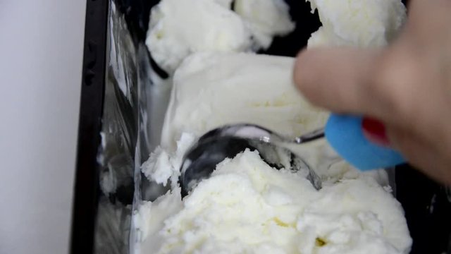 Vanilla ice cream Flat lay. Top view. Spoon for ice cream takes a little out of the package. Macking ball of ice cream.