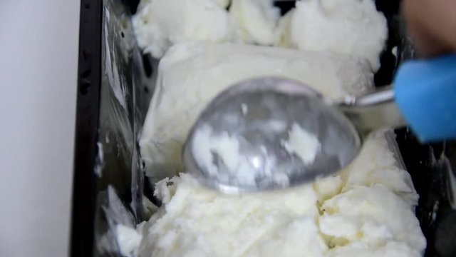 Vanilla ice cream Flat lay. Top view. Spoon for ice cream takes a little out of the package. Macking ball of ice cream.