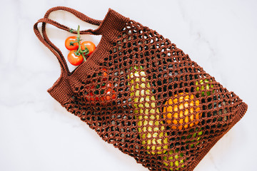 Still life of brown biodegradable shopping bag with raw vegetables on marble background, top view, flat lay