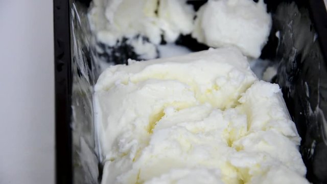 Vanilla ice cream Flat lay. Top view. Spoon for ice cream takes a little out of the package. Macking ball of ice cream.