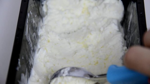 Vanilla ice cream Flat lay. Top view. Spoon for ice cream takes a little out of the package. Macking ball of ice cream.